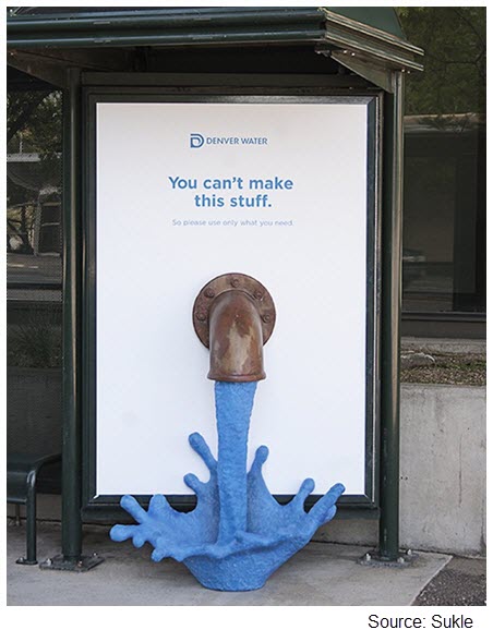 Photo of a bus stop with a sign showing a spout with water coming out of it reading You can't make this stuff.